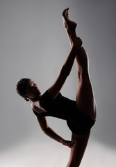 A flexible young female gymnast in sportswear performs a stretch. Sports motivation, physical education