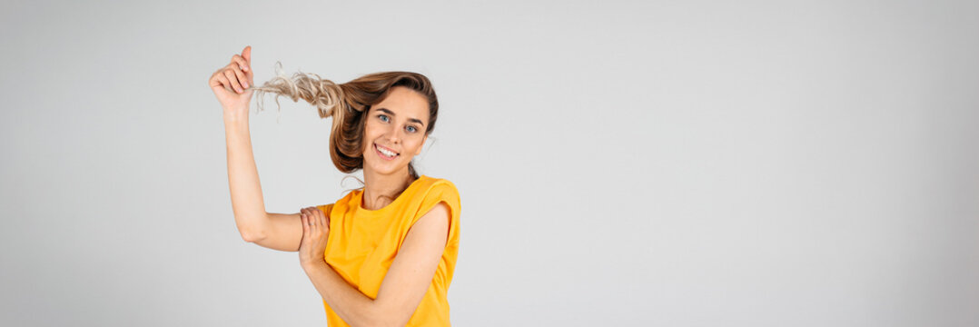 Web banner of a beautiful woman on a white background twisting her hait on the fingure, empty space