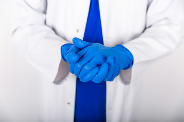 Treatment of blue rubber gloves with an antiseptic against bacteria. The doctor uses an antiseptic with blue gloves. Doctor in a white coat and protective gloves. The use of a disinfectant with gloves