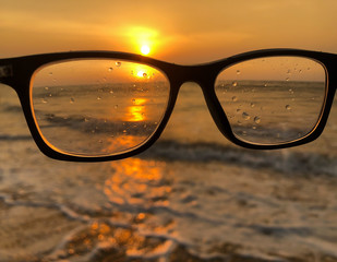 A pair of glasses at the beach with the sunset and how unclear life is to a person without a pair...