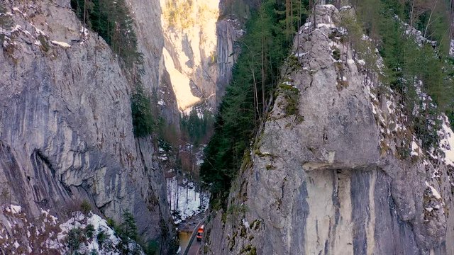 Aerial drone view of a serpentine in rocky mountain forest, Bicaz gorge with winding road in winter season,Cheile Bicazului, Romania