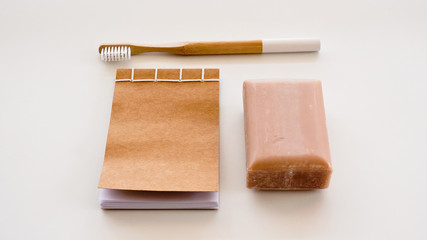 Zero waste minimal set including bamboo toothbrush, craft natural soap, recycled paper notepad on white background