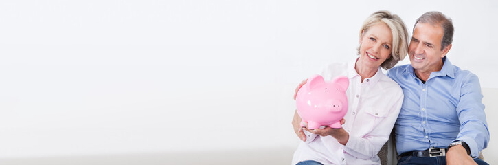 Mature Couple Calculating Coin In The Piggybank