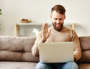 Cheerful man having online conversation on laptop with friend.