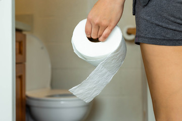 A person using toilet paper in the bathroom.