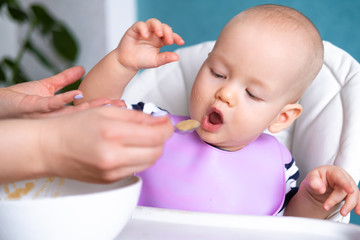 baby food. Mom feeds little caucasian child. healthy porridge, mother hands with spoon. Newborn infant kids.