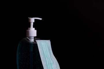 Hand sanitizer antibacterial antiseptic gel and face mask  on dark background.