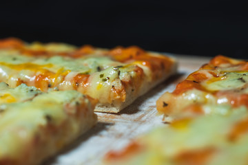 Close up flat bread pizza by cheese on a cutting board with flour in black background