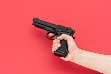 Men holding black revolver gun isolated on the red background.