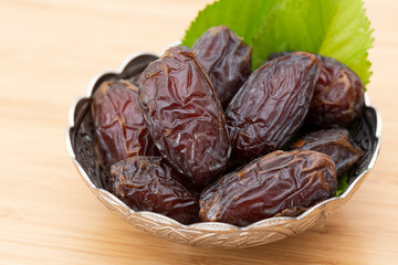 Palm dates on the silver plate, wooden background.