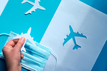 Restart flying, end quarantine. Hand holding paper plane over face mask takes it from shadow to...