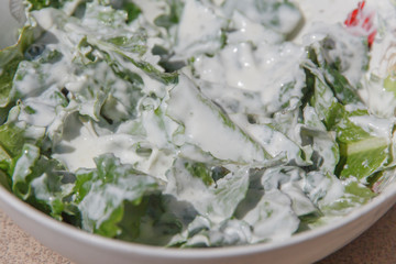 green lettuce in sour cream in a white plate