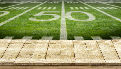Empty wooden table and sports field american football field background