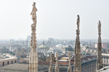 Statues of the dome looking over the cityscape of Milan, Italy on a sunny day