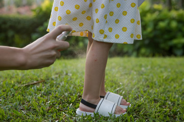 Mother applying mosquito and bugs repellent spray on her toddler girl.