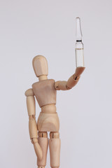 Wood figurine holding a white vaccine vial