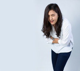 Sick Asian woman having a stomach ache on white background. Female holds hands on abdomen