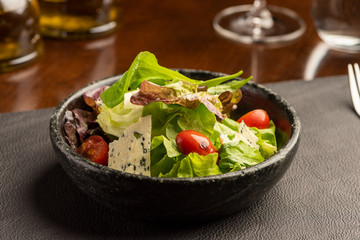 Salad with green lettuce and green leaves with blue cheese and tomatoes on a bowl