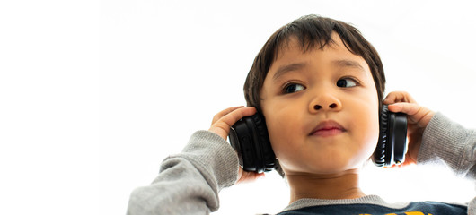 Family, home, technology and music concept. Portrait Young little Asian boy listening music with headphones at home. School child listening loud music in wireless earphones