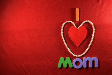 Colorful letters with I love mom isolated on red cloth background. I love mom spelled with colorful letters and red heart for mothers day. Mother's day gift box.