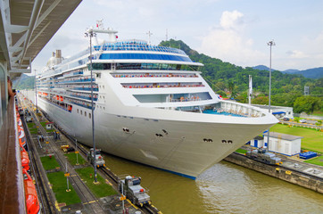 Modern white Panamax cruiseship or cruise ship liner transit through old Miraflores locks at Panama...