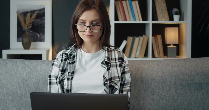 Beautiful young woman eyewear and checkered shirt spending leisure time at home and using laptop. Concept of people, technology and free time.