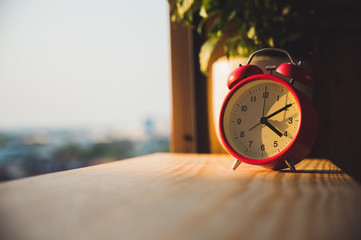 Alarm Clock on wooden in the morning with sunlight.