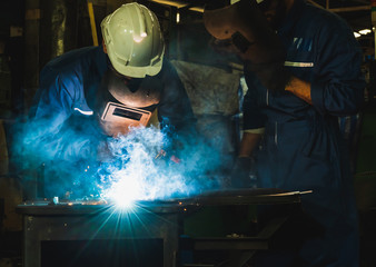 Industrial worker welding metal with many sharp sparks