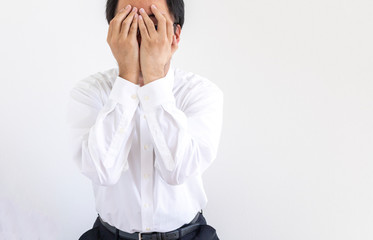 両手で顔を隠している、ワイシャツを着た男性