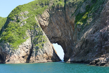 Huge hexagonal columnar joints of volcanic rock at Hong Kong Global Geopark, China, with cave made...
