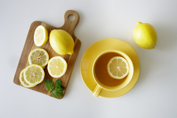 cup of tea with fresh yellow lemons on white background