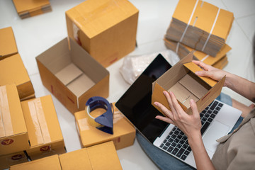 Female business owner working, packing the order for shipping to customer. Female entrepreneur...