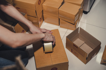 Female business owner working, packing the order for shipping to customer. Female entrepreneur...