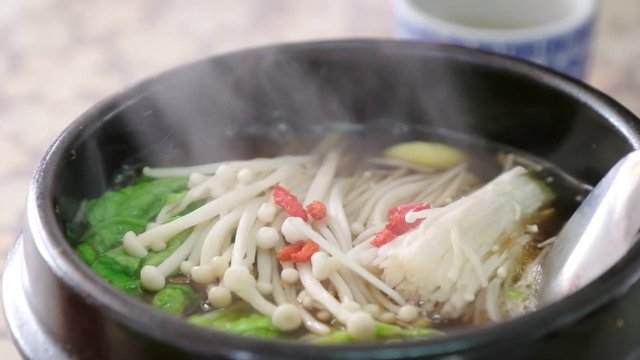 close up of tasty yummy delicious Asian food hot herbal soup call "Bak kut teh soup" with smoke , pork rib with vegetable dish cooked in broth popularly served in Thailand 