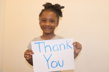 Young Girl holding homemade Thank You sign indoors