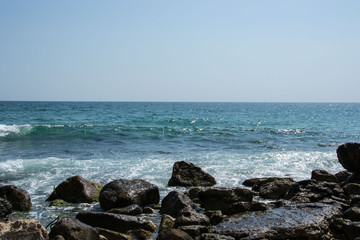 Beautiful wild beach landscape, sunny day, water waves hitting the cliffs, nature summertime scene