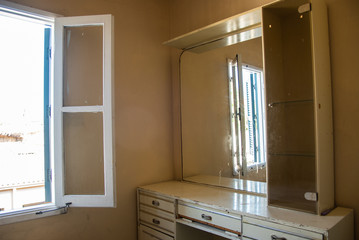 Interior of an old abandoned bedroom with open windows