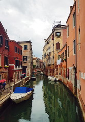 Fototapeta na wymiar Venetian canal with boats, ancient low-rise houses, cafes and shops