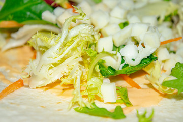 Leafy salad, sliced vegetables and pita sauce are the basis for homemade Shawarma. Close up.