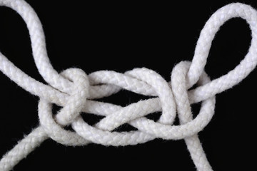 A white rope tied with chair knot on black background.