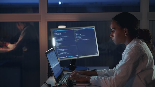 Side view of african american female engineer working on computer in electronics laboratory. Doing Development of Software and Hardware. She wearing a lab coat