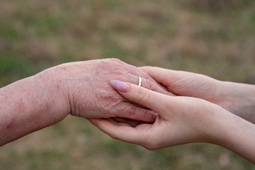 The hand of an elderly woman and the hands of a teenage girl.