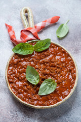 Serving pan with freshly cooked bolognese sauce and green basil leaves, selective focus, studio shot