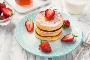 Cottage cheese pancakes with sliced strawberry on white background for breakfast.