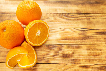 two whole and sliced orange on a wooden background top view