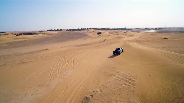 Black lifted 4x4 truck with racing decals drives away from the camera; desert racing.