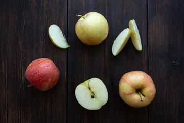 three apples with a slices of water drops on a dark wooden background top view