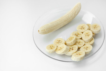 banana and slices in a plate on a white background
