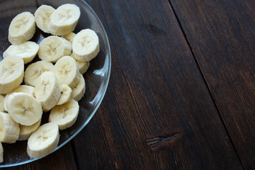 banana slices in a plate on a dark wooden background