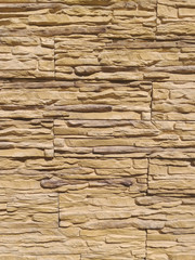Texture of a stone wall in soft brown color close-up. Decorative stone wall. Wall with narrow masonry stones. Design pattern